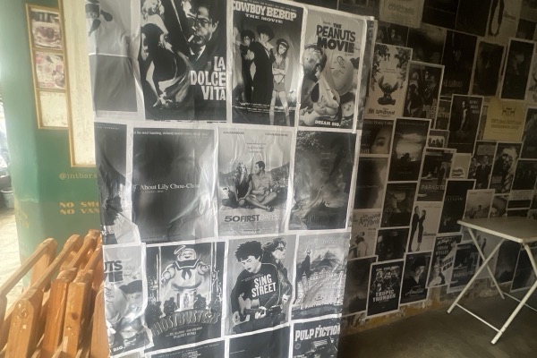 The wall outside EXT.Cafe covered floor to ceiling in black-and-white film posters.