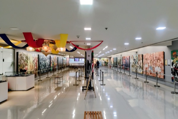 Inside Gateway Gallery: a long white hall with large paintings along both walls and bunting overhead.