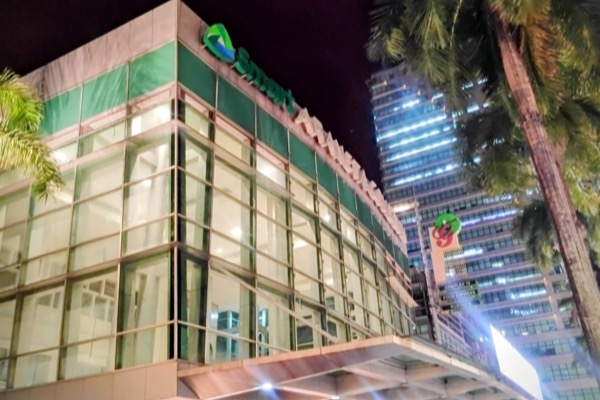The green and glass front of the Smart Araneta Coliseum lit up at night, the Smart sign above it.